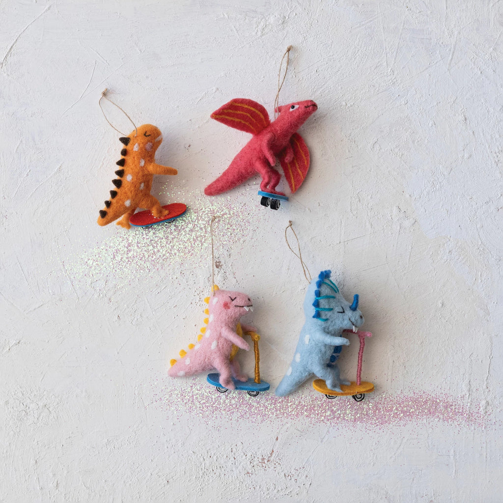 Add a playful touch to your holiday decor with these handmade wool felt dinosaur ornaments, available in four different colors. Each unique ornament features a fun dinosaur riding a skateboard or scooter, giving your tree a quirky and fun vibe. Make your holidays a little more "rawrsome" with these adorable ornaments! Orange, Red, Pink & Blue