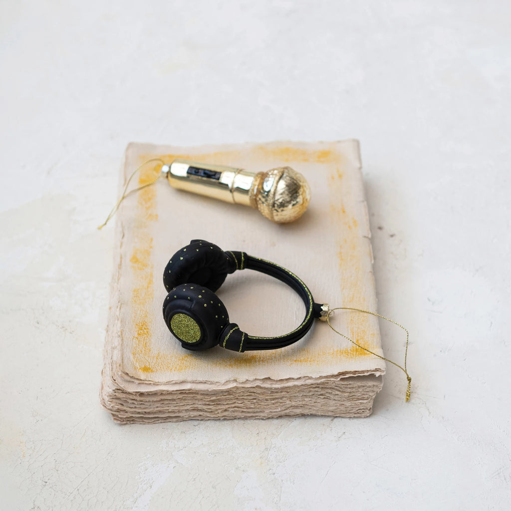 This glass and resin headphones ornament is a nod to audiophiles and the holiday season. Clad in black with touches of green glitter, it's a visual representation of the joy music brings, ready to adorn any tree with a bit of rhythm and sparkle.