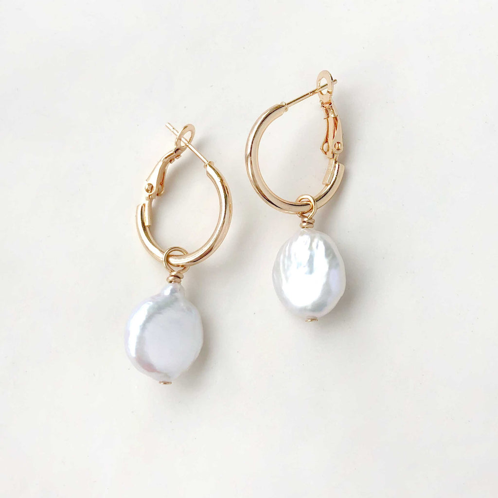 Rock these unique Coin Pearl Hoops and elevate your style. Each natural coin pearl is delicately suspended on a gold plated leverback for a touch of elegance. Add a quirky flair to your outfit with these playful hoops.